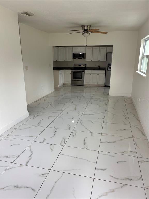 A kitchen with white cabinets and stainless steel appliances opens to a tiled dining area — 519 KATHERINE AVENUE, ORLANDO, FL