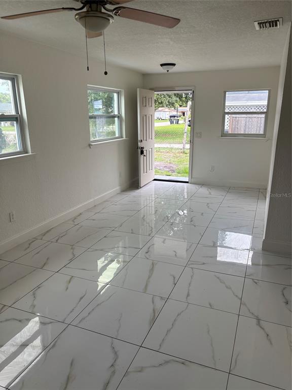 A room with white marble-look tile flooring, a ceiling fan, and an open exterior door — 519 KATHERINE AVENUE, ORLANDO, FL