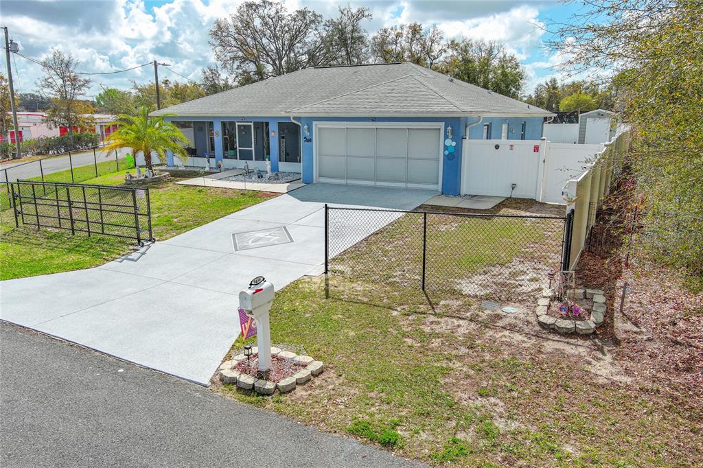 A blue single-story house with a white garage door and a chain-link fence — 9430 SE 158TH STREET, SUMMERFIELD, FL