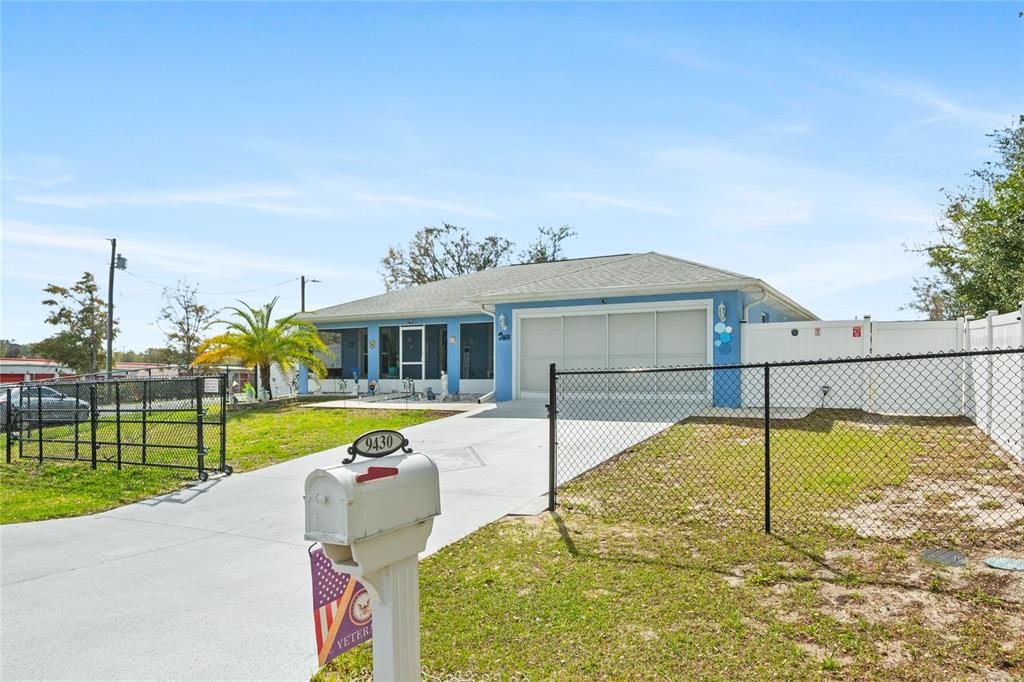 A light blue house features a screened-in front porch with a central door and walkway — 9430 SE 158TH STREET, SUMMERFIELD, FL