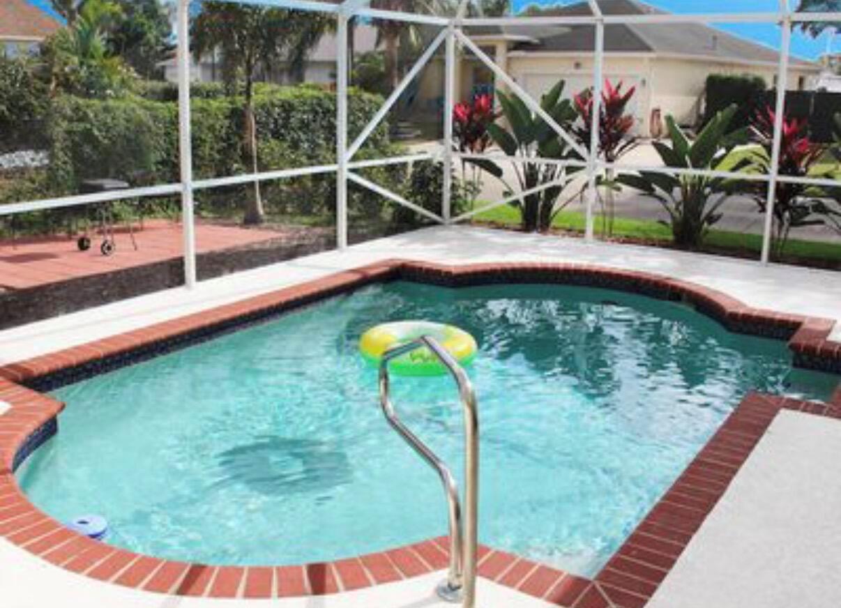 A screened-in swimming pool with a brick border and a metal handrail in a backyard — 1608 Doral Drive, FL 33413, FL