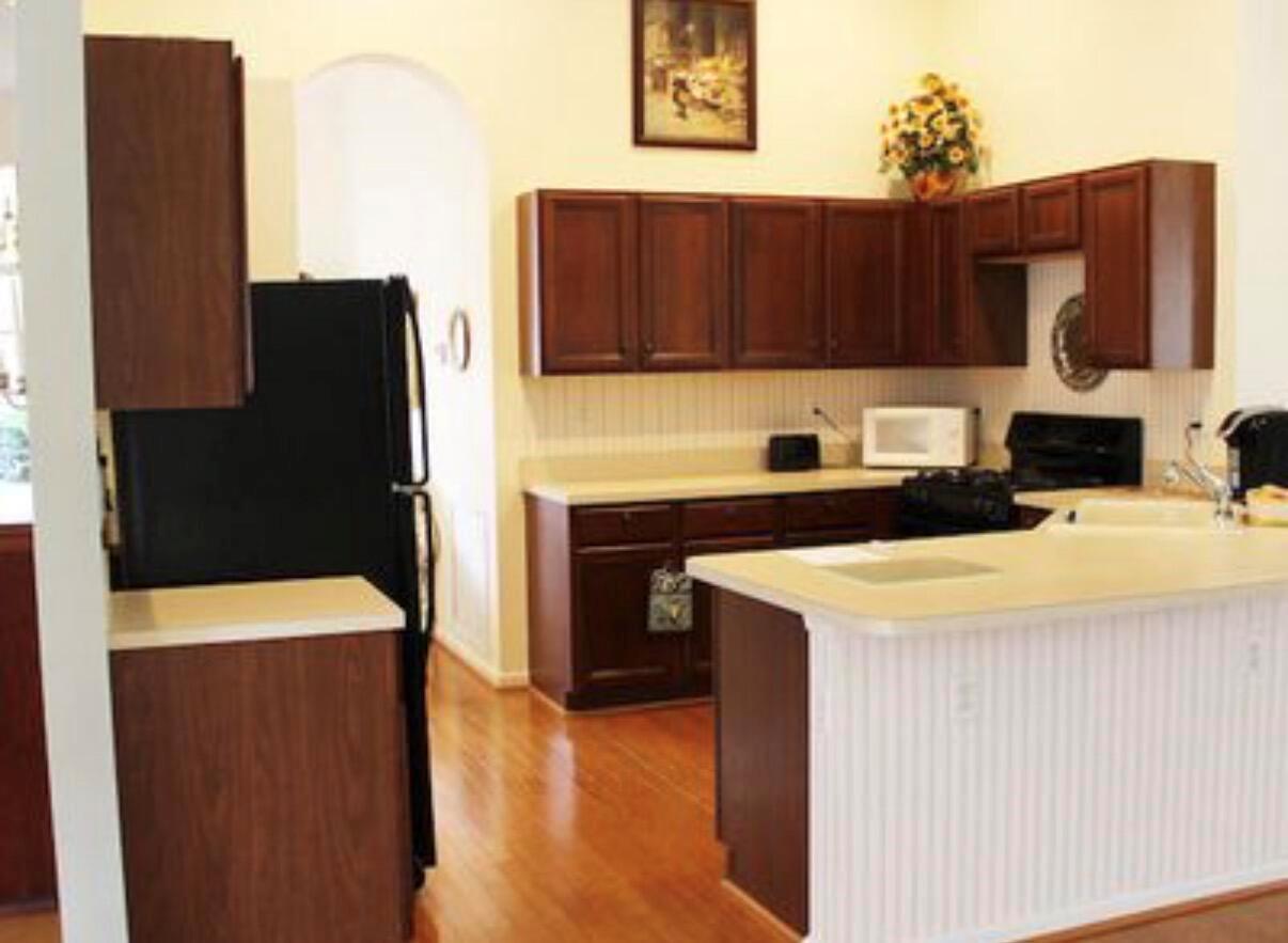 A kitchen features dark wood cabinets, light countertops, a black refrigerator, and hardwood flooring — 1608 Doral Drive, FL 33413, FL