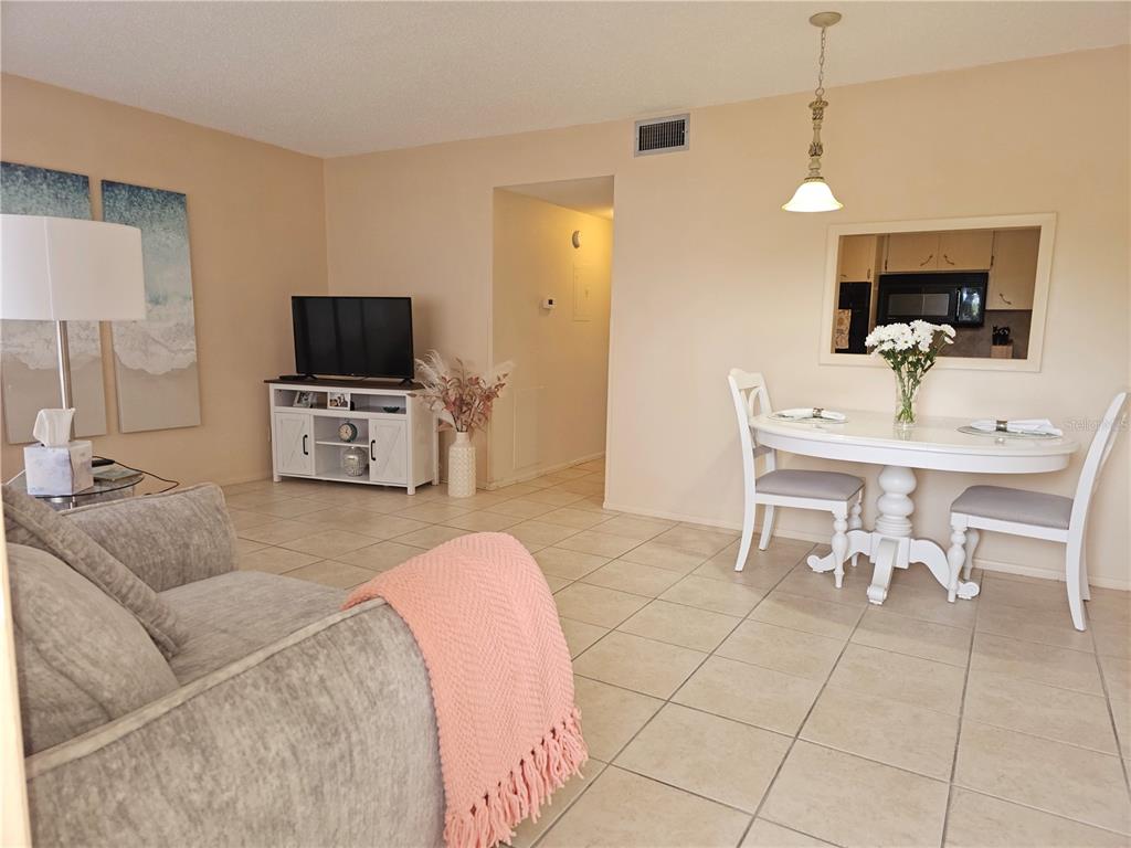 A living and dining area with tile floors, a television console, and a dining set — 2458 COLUMBIA DRIVE UNIT 66, CLEARWATER, FL