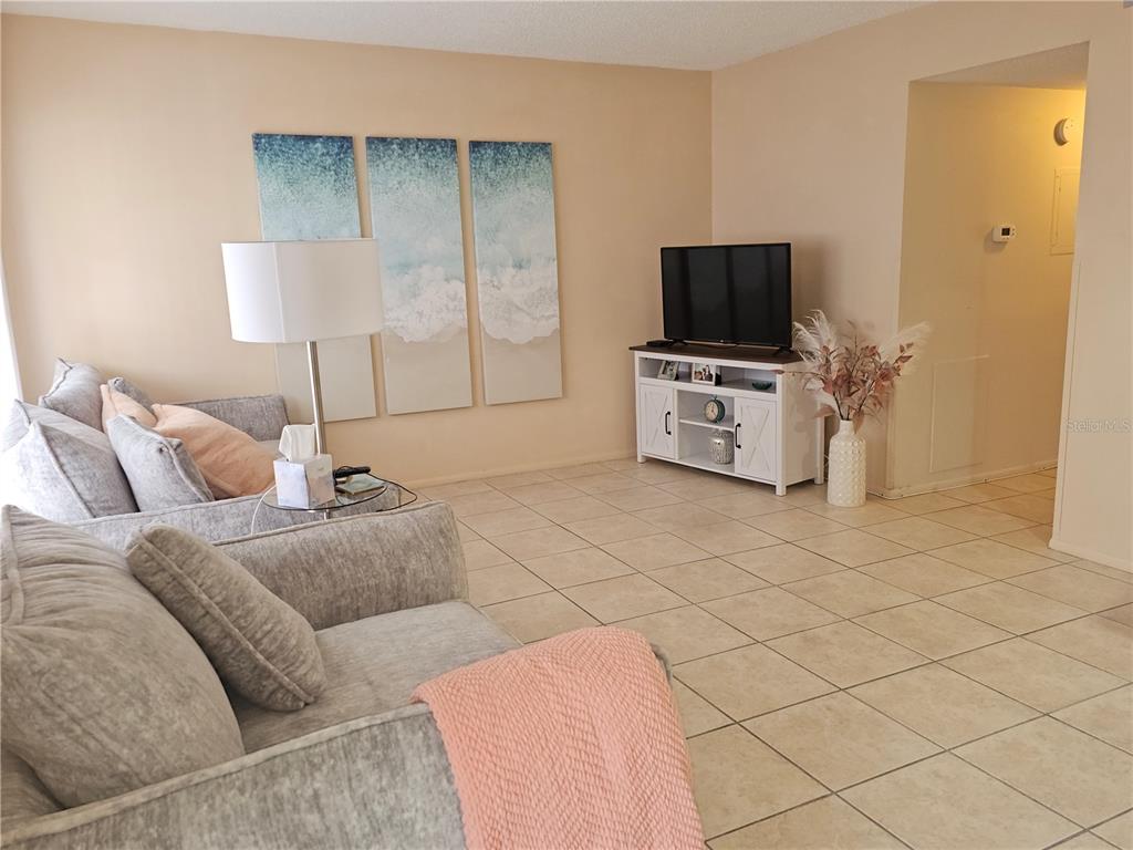 A living room features light tile floors, a grey sofa, and a white media console — 2458 COLUMBIA DRIVE UNIT 66, CLEARWATER, FL