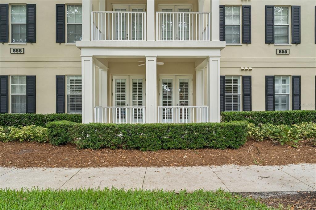 The exterior of a multi-story apartment building features balconies, white railings, and dark window shutters — 855 BLUE SAGE STREET UNIT 102, CELEBRATION, FL