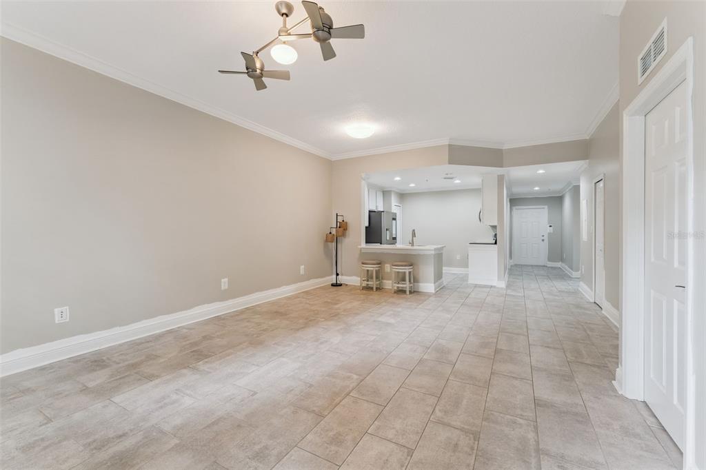 An open-concept living area with tile flooring, a kitchen breakfast bar, and a ceiling fan — 855 BLUE SAGE STREET UNIT 102, CELEBRATION, FL