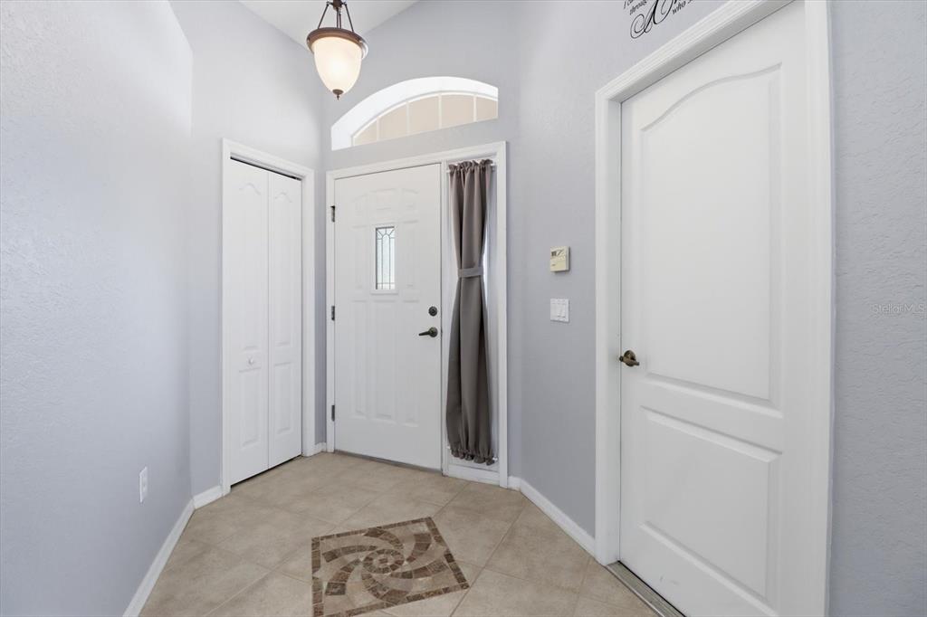 An entryway features light gray walls, tile flooring with a decorative inlay, and white doors — 250 ROYAL PALM WAY, SPRING HILL, FL