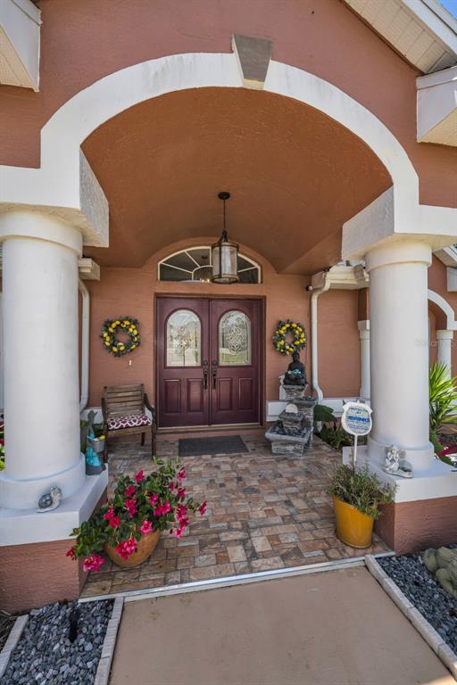 The front entrance features a covered porch with two white columns and double doors — 11210 AUBURNDALE STREET, SPRING HILL, FL