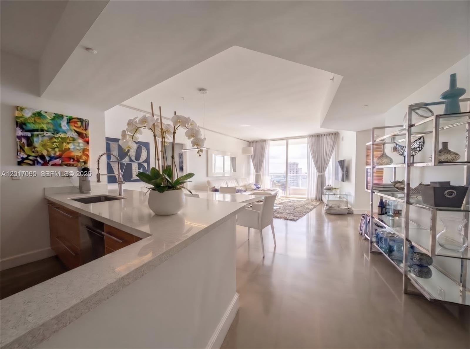 A modern kitchen with a white quartz island overlooks an open-concept living and dining area — 400 Alton Rd # 1709, Miami Beach FL 33139, MIAMI BEACH, FL
