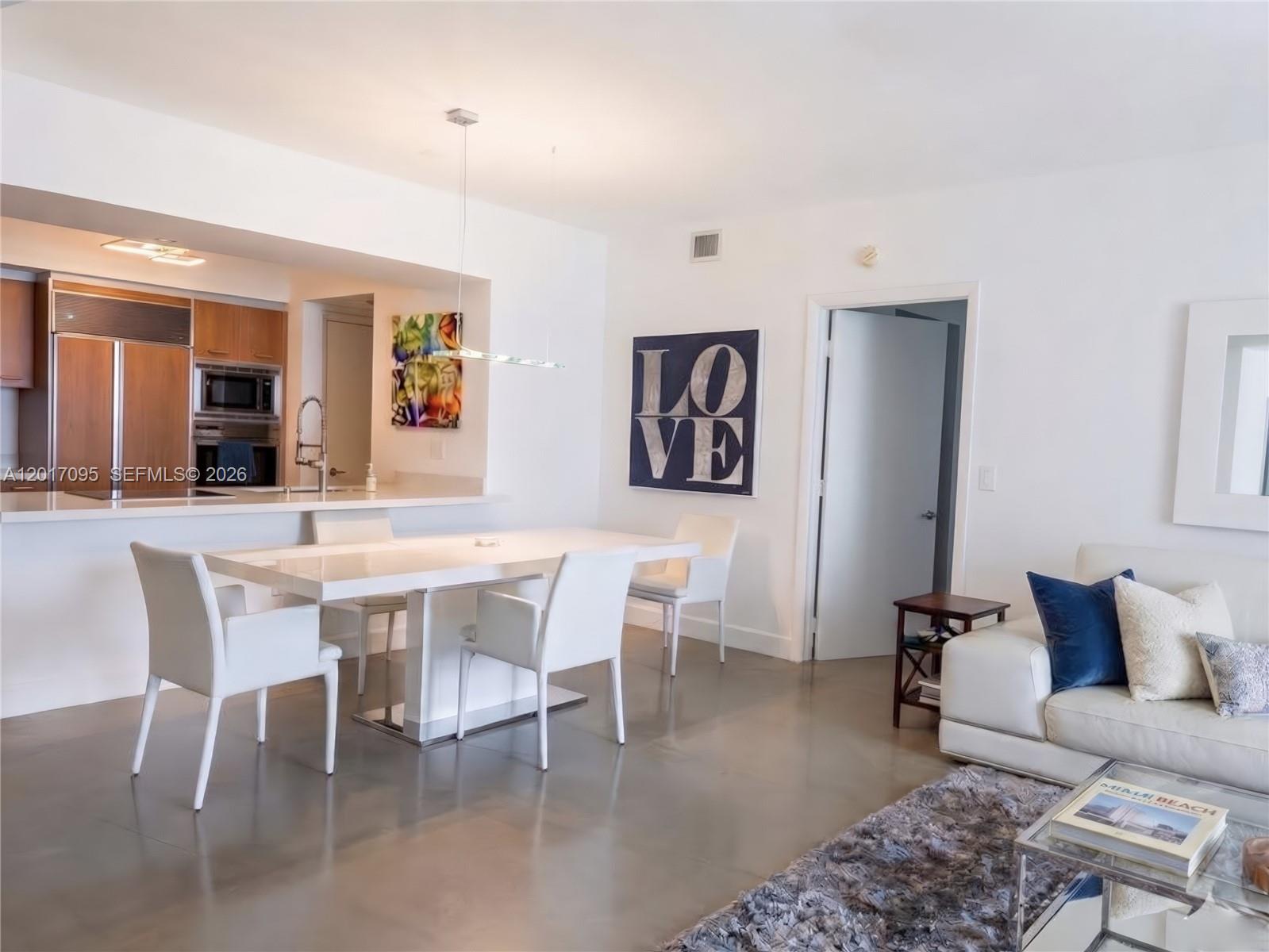 A dining area with a white table and chairs sits adjacent to an open kitchen — 400 Alton Rd # 1709, Miami Beach FL 33139, MIAMI BEACH, FL