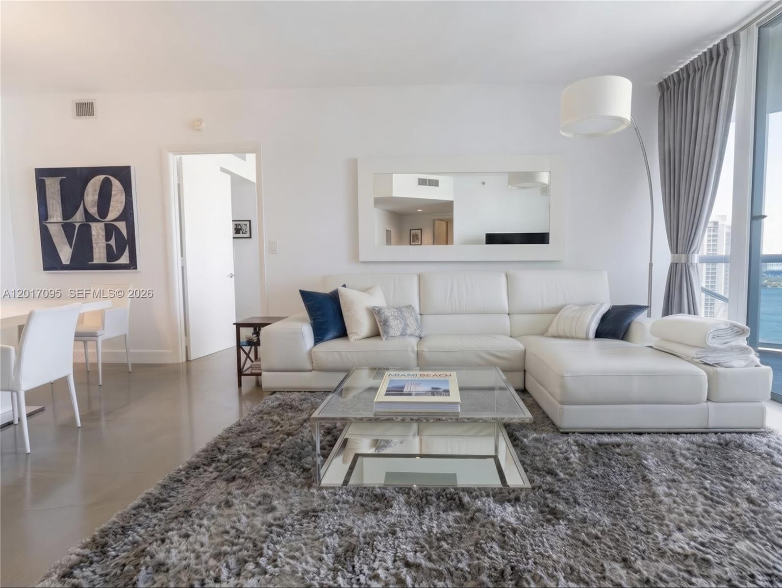 A modern living room features a white sectional sofa, glass coffee table, and gray rug — 400 Alton Rd # 1709, Miami Beach FL 33139, MIAMI BEACH, FL
