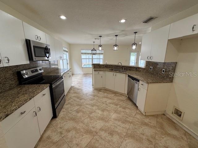 A kitchen features white cabinets, granite countertops, stainless steel appliances, and tile flooring — 11722 CREST CREEK DRIVE, RIVERVIEW, FL