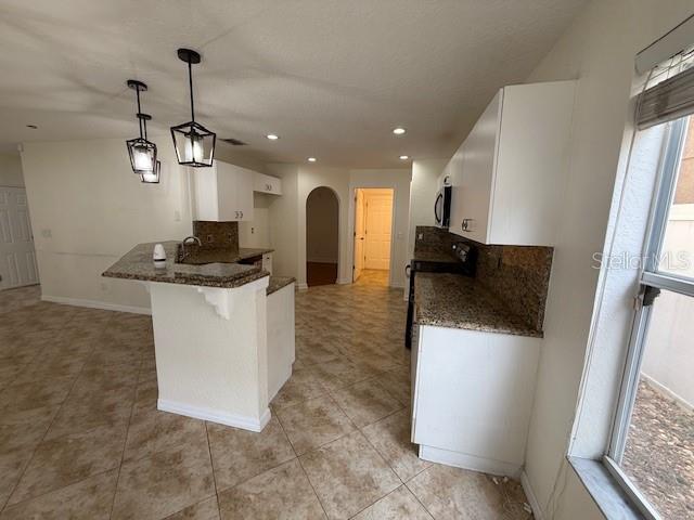 A kitchen features white cabinets, granite countertops, tile flooring, and two hanging pendant lights — 11722 CREST CREEK DRIVE, RIVERVIEW, FL