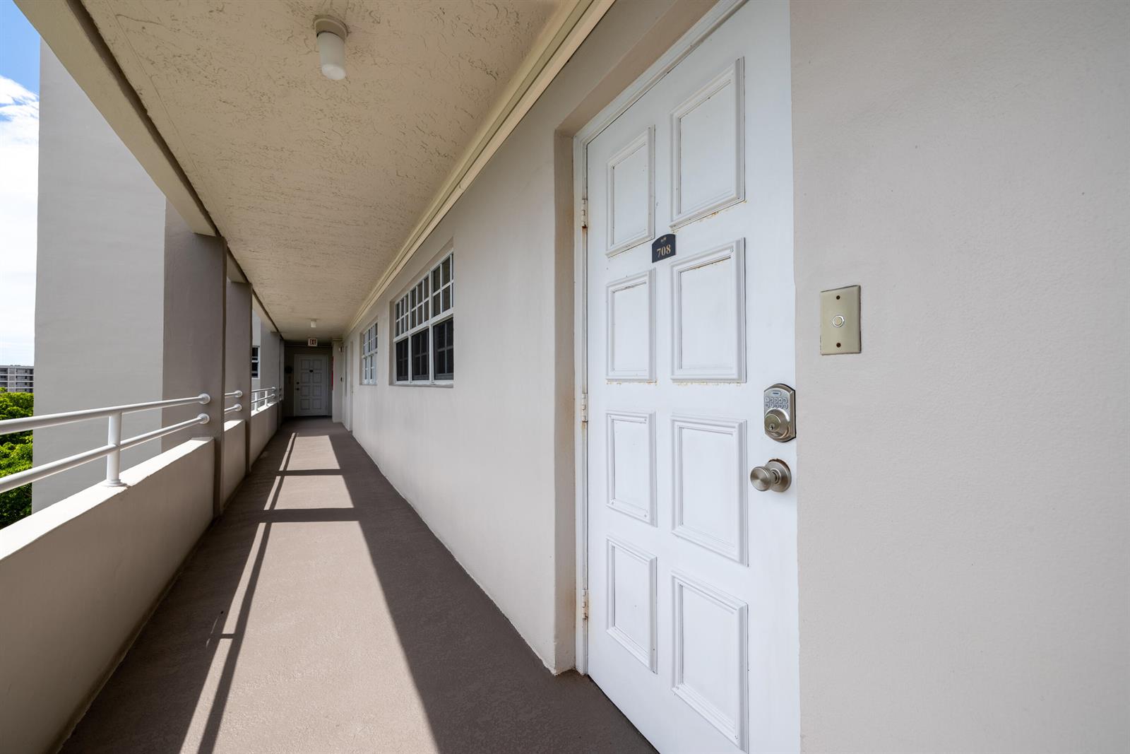 A white door with a keypad lock sits along an outdoor apartment building walkway — 575 Oaks Lane # 708, Pompano Beach FL 33069, POMPANO BEACH, FL