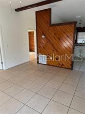A room with light-colored tile flooring features a prominent diagonal wood-paneled accent wall — 1207 3RD AVENUE E UNIT A & B3400, BRADENTON, FL