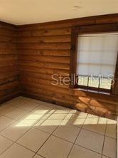 A room with light-colored tile flooring and horizontal wood-paneled walls featuring a single window — 1207 3RD AVENUE E UNIT A & B3400, BRADENTON, FL