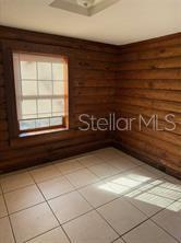 A room with horizontal wood-paneled walls, a single window, and light-colored square floor tiles — 1207 3RD AVENUE E UNIT A & B3400, BRADENTON, FL