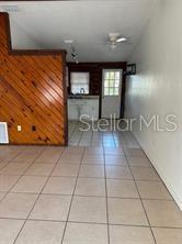 A room with light-colored floor tiles, a wood-paneled wall, and a doorway leading outside — 1207 3RD AVENUE E UNIT A & B3400, BRADENTON, FL