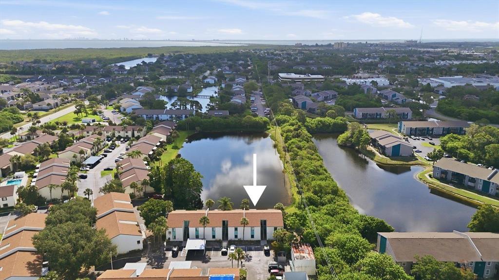 An aerial view shows a multi-unit residential building situated next to a pond — 11409 8TH STREET N UNIT 1509, ST PETERSBURG, FL