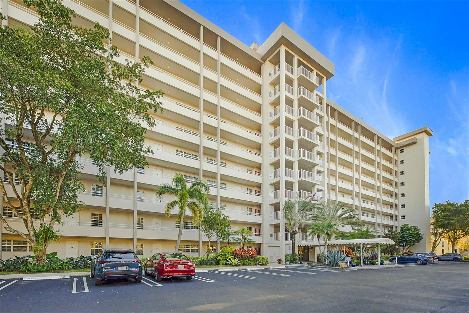 A multi-story apartment building with balconies and a parking lot in front — 575 Oaks Lane # 703, Pompano Beach FL 33069, POMPANO BEACH, FL