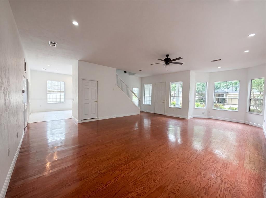 A spacious living room features hardwood floors, a ceiling fan, and large windows — 9405 SW 31ST LANE, GAINESVILLE, FL