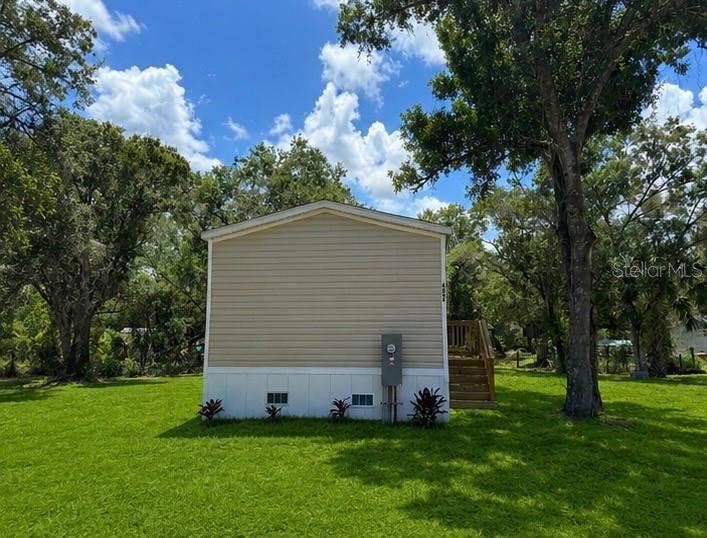 The exterior side of a tan manufactured home features a wooden staircase and electrical meter — 6042 SW MIAMI AVENUE, ARCADIA, FL