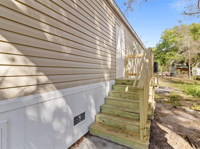 A side view of a manufactured home with beige siding and a wooden staircase — 6042 SW MIAMI AVENUE, ARCADIA, FL
