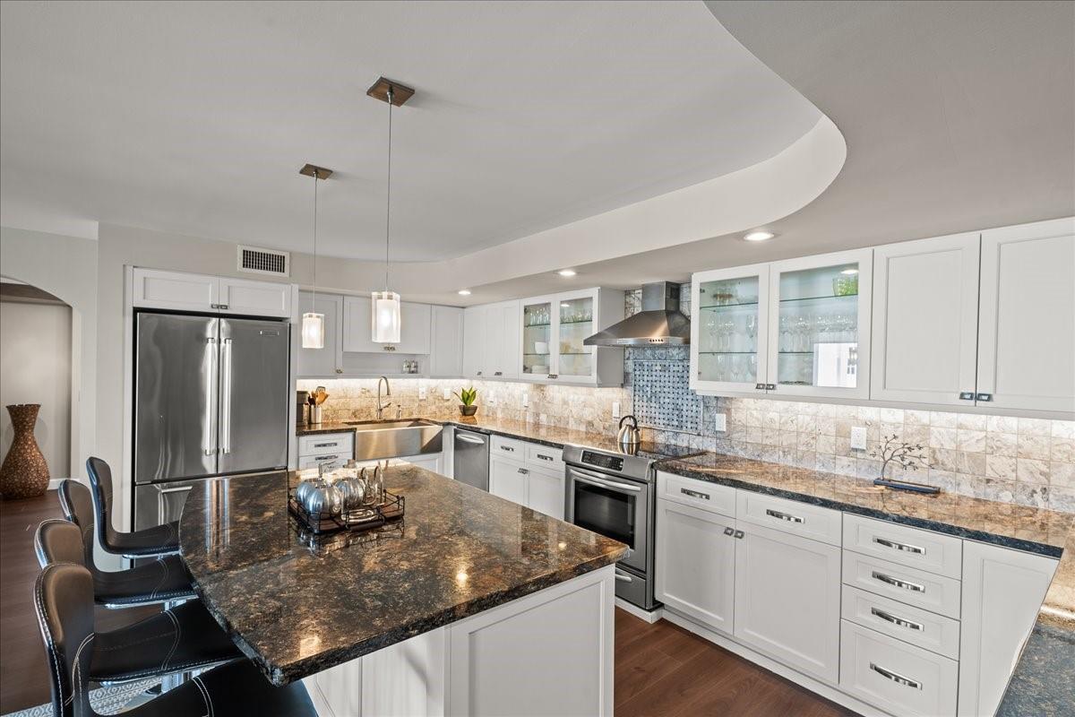 A kitchen features white cabinetry, dark granite countertops, a center island, and stainless steel appliances — 1890 S Ocean Drive, Hallandale Beach FL 33009, HALLANDALE BEACH, FL