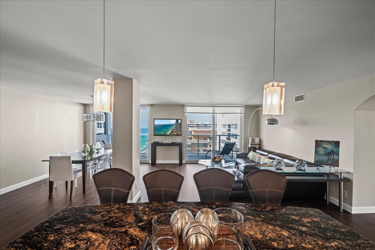An open-concept living and dining area features dark wood floors, granite countertops, and ocean views — 1890 S Ocean Drive, Hallandale Beach FL 33009, HALLANDALE BEACH, FL