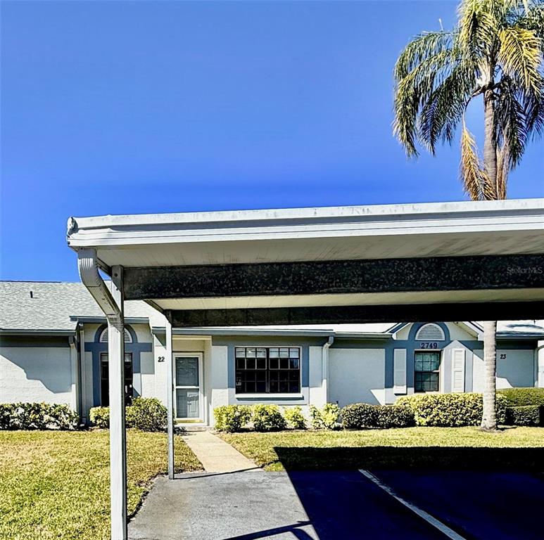 A view of a single-story residential building exterior with a covered carport in the foreground — 2749 COUNTRYSIDE BOULEVARD UNIT 22, CLEARWATER, FL