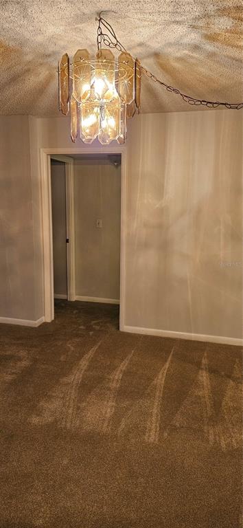 A room with brown carpet, a textured ceiling, and a vintage amber glass chandelier — 2617 COVE CAY DRIVE UNIT 311, CLEARWATER, FL
