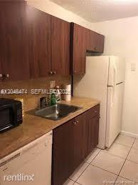 A kitchen features dark wood cabinets, a stainless steel sink, and a white refrigerator — 7401 SW 152nd Ave # 1, Miami FL 33193, MIAMI, FL
