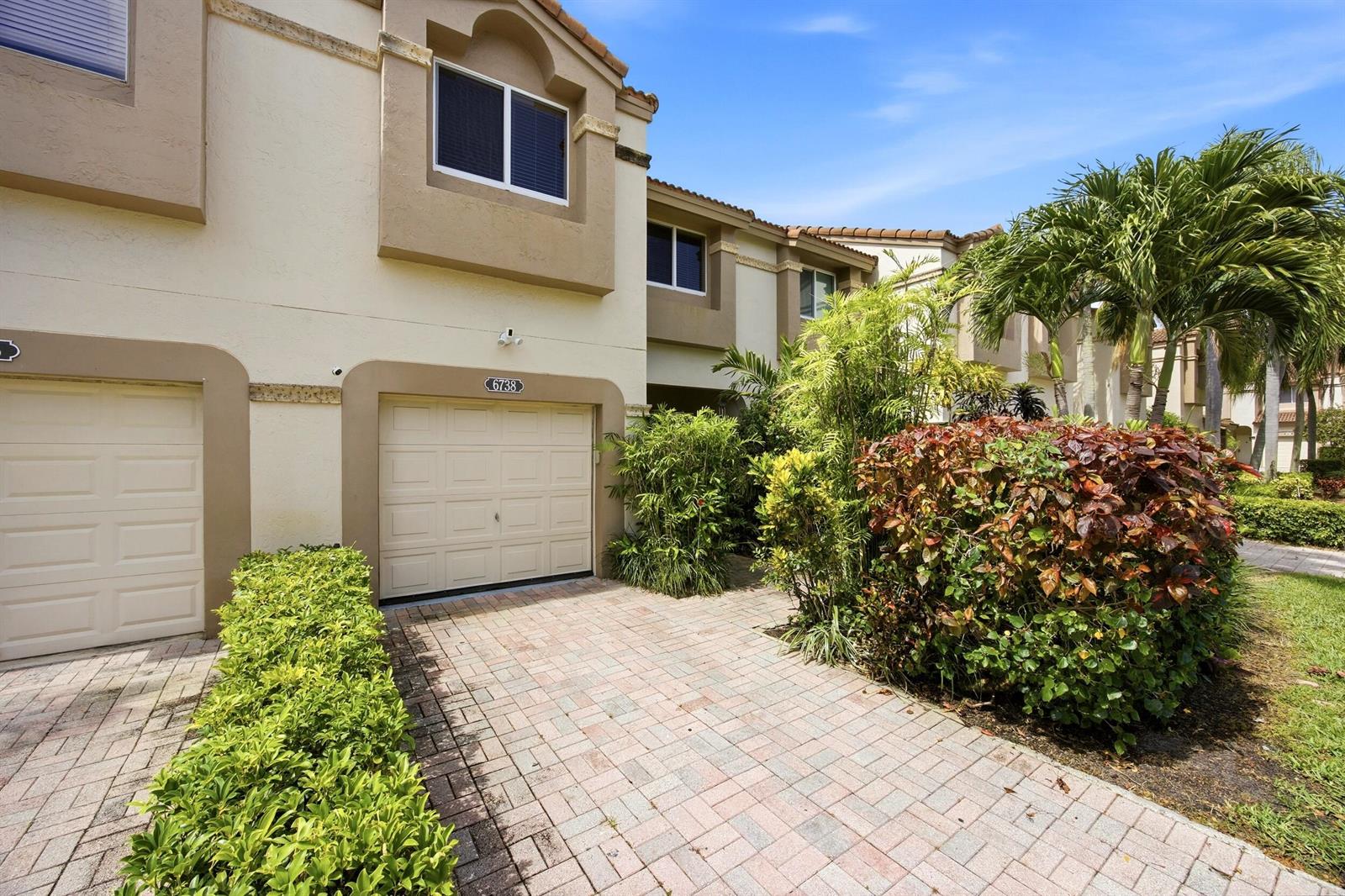 Exterior view of a two-story townhouse with a paved driveway and a garage — 6738 Via Regina, Boca Raton FL 33433, BOCA RATON, FL