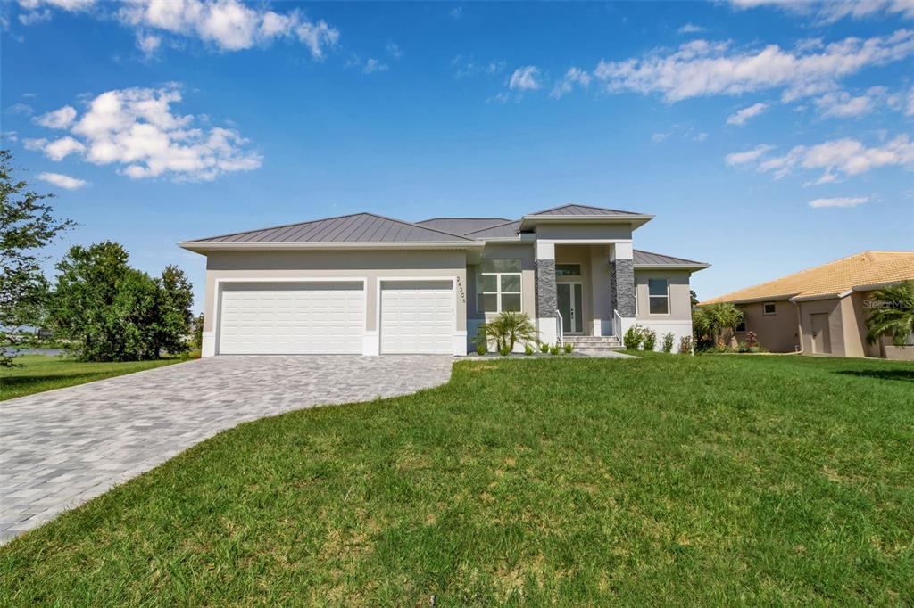 A single-story house with a metal roof, two-car garage, and a paved driveway — 24206 SANTA INEZ ROAD, PUNTA GORDA, FL
