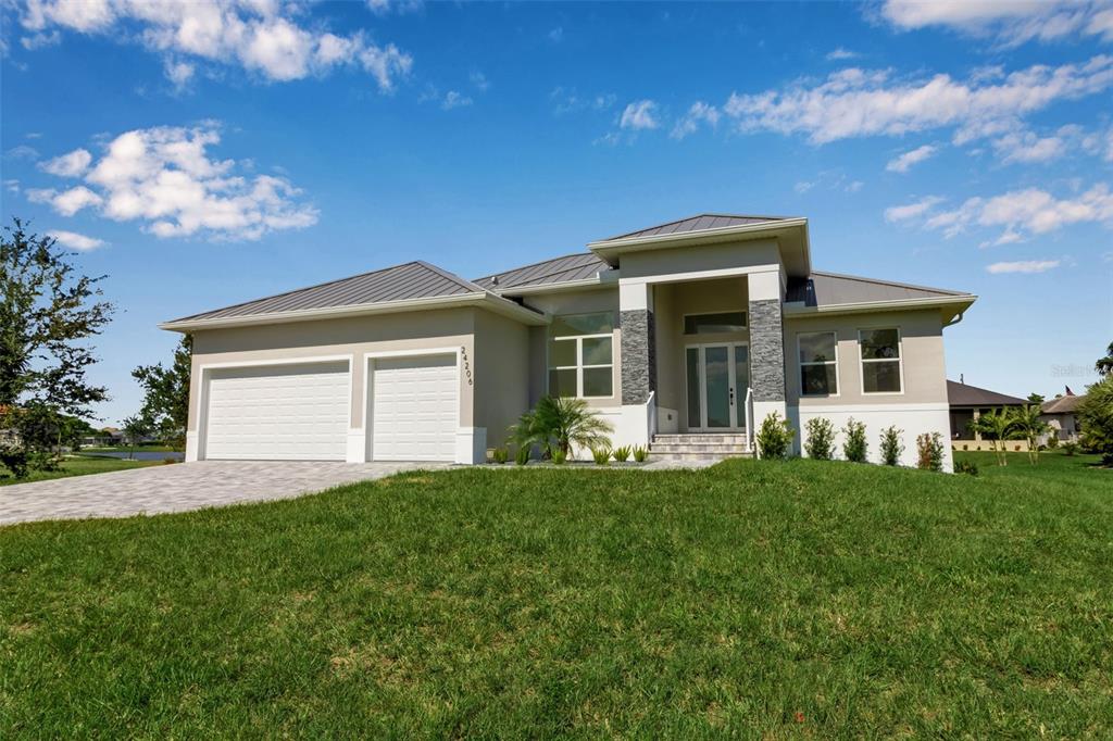 A single-story house with a metal roof, stone accents, and a two-car garage — 24206 SANTA INEZ ROAD, PUNTA GORDA, FL