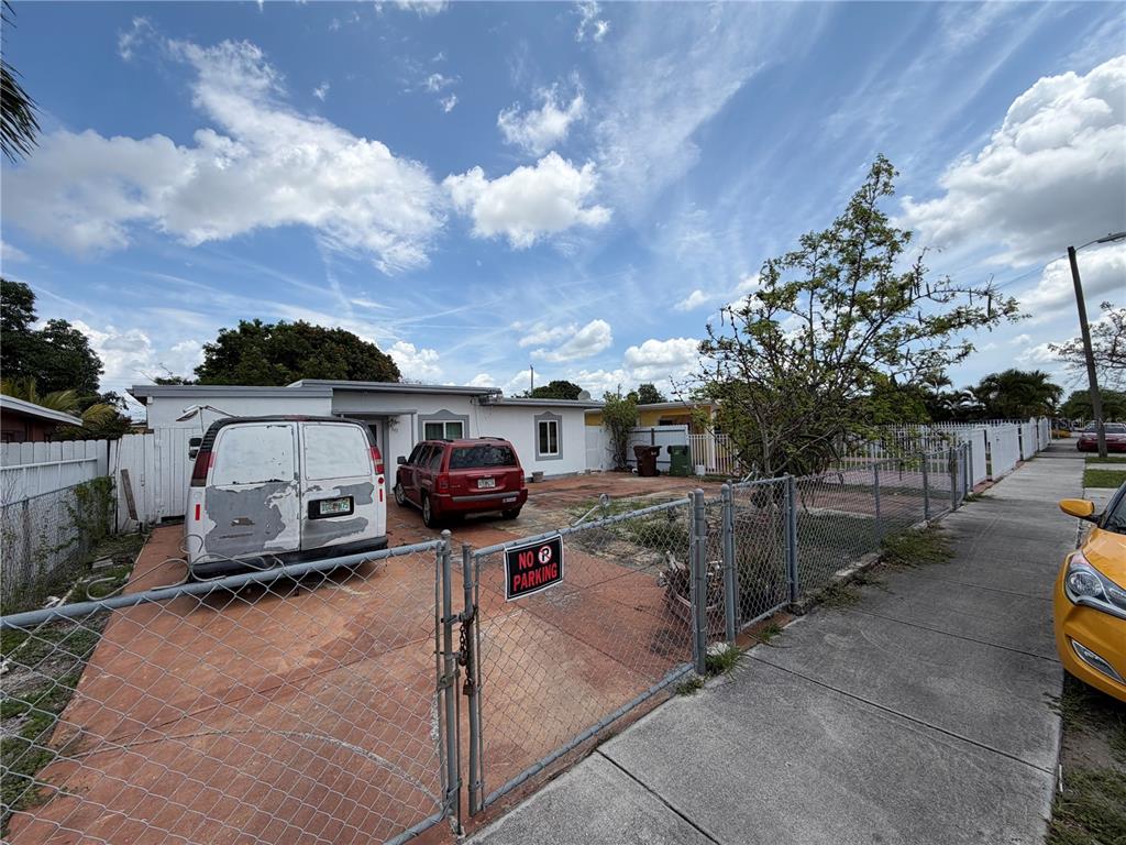 A fenced-in front yard with a paved driveway, a white van, and a red SUV — 445 E 43RD STREET, HIALEAH, FL