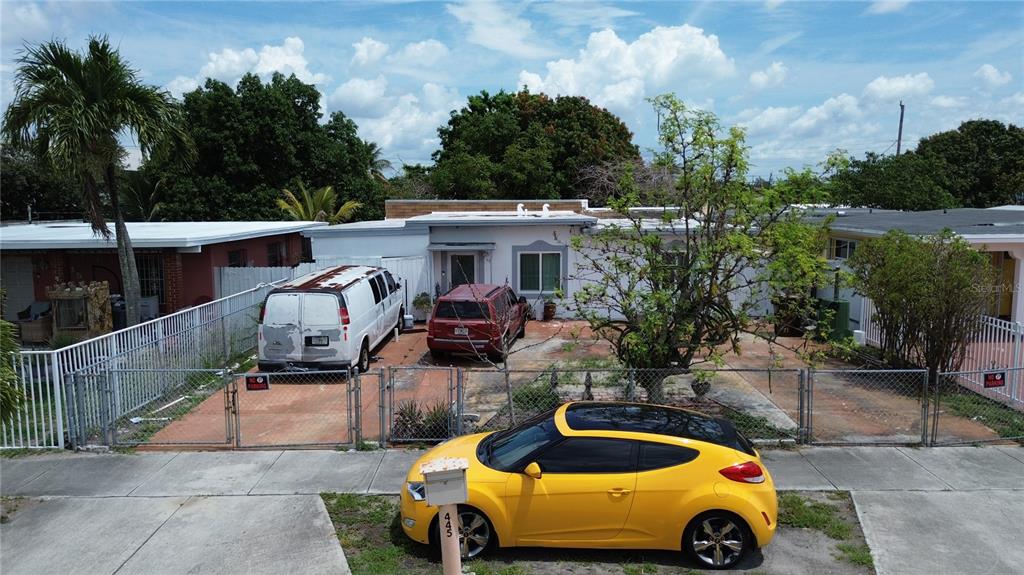 An exterior view of a single-story house with a fenced front yard and parked vehicles — 445 E 43RD STREET, HIALEAH, FL
