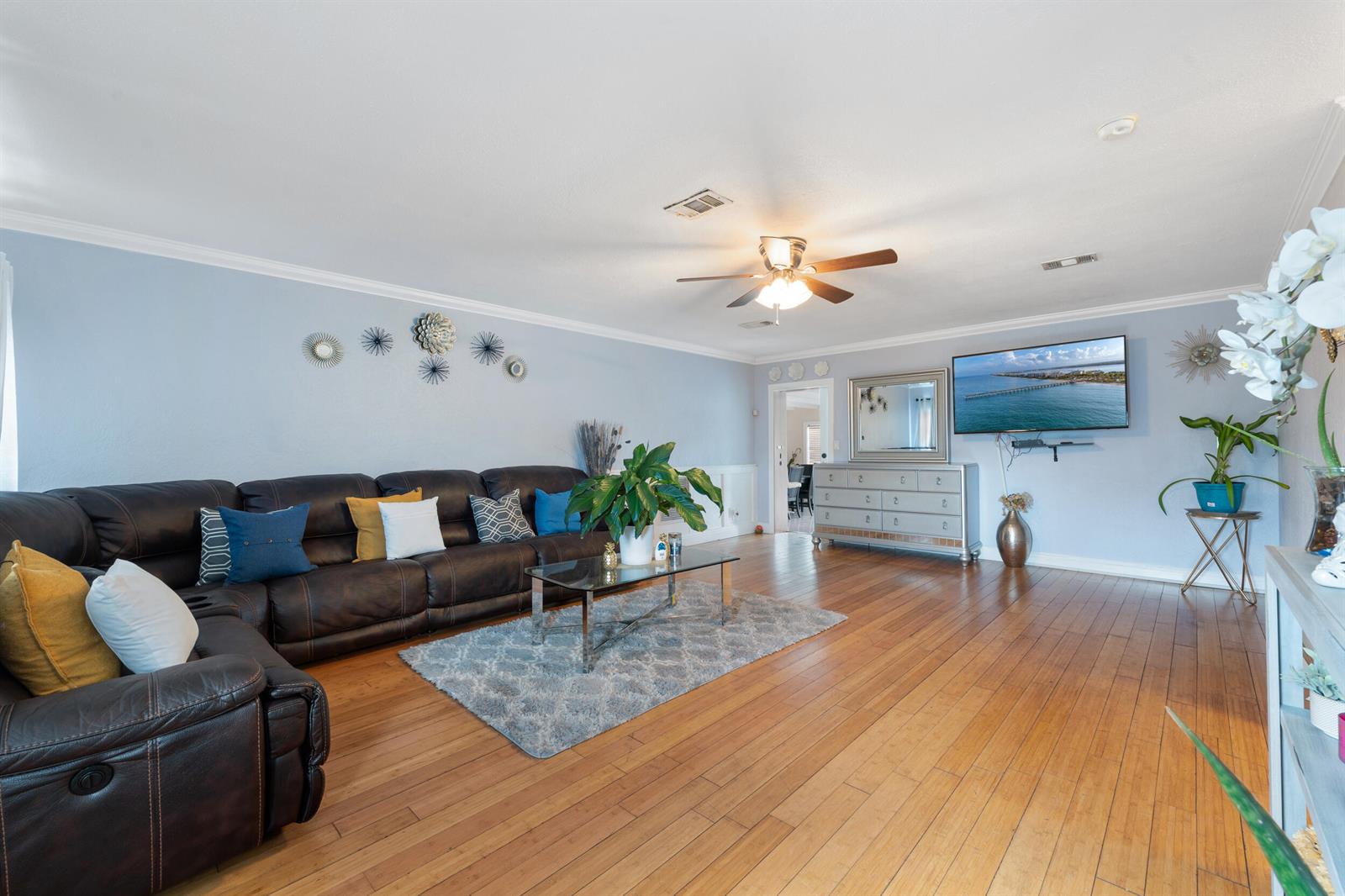 A living room features a dark leather sectional, hardwood floors, and a wall-mounted television — 808 Wright Drive, Lake Worth FL 33461, LAKE WORTH, FL
