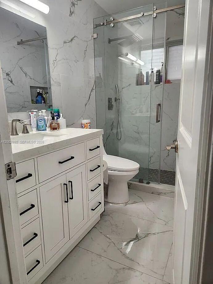 A modern bathroom features a white vanity, marble-look tile flooring, and a glass-enclosed shower — 12011 NW 33rd St, Sunrise FL 33323, SUNRISE, FL