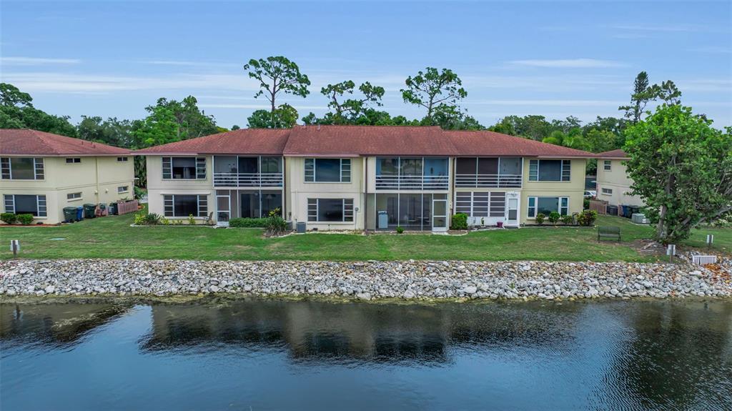 An exterior view of a two-story apartment building with screened balconies overlooking a canal — 4470 NARRAGANSET TRAIL UNIT 90A, SARASOTA, FL