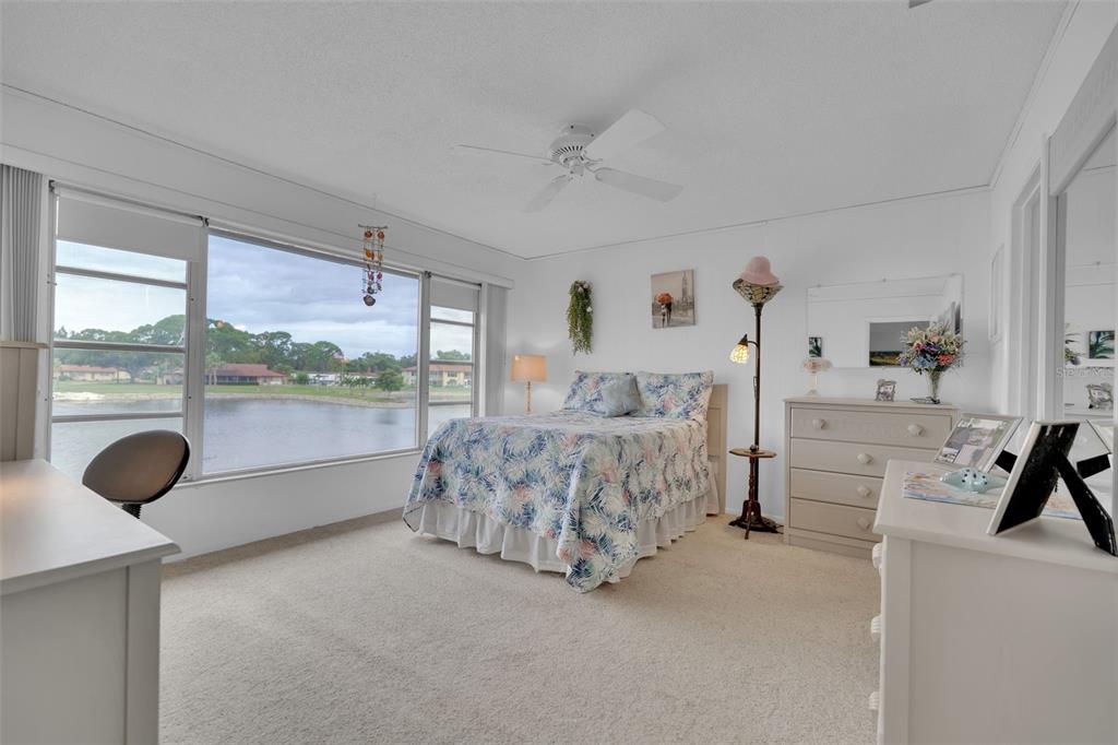 A bedroom with a queen bed, white furniture, carpeted floors, and a large waterfront window — 4470 NARRAGANSET TRAIL UNIT 90A, SARASOTA, FL
