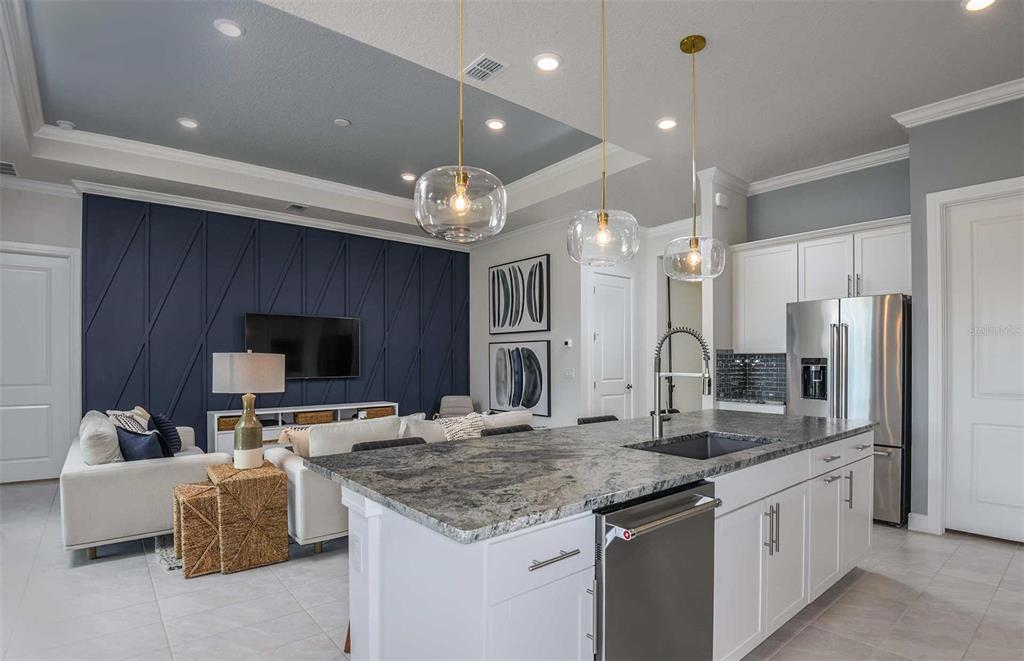 An open-concept kitchen and living area featuring a blue accent wall and granite island — 5778 SW 82ND TERRACE ROAD, OCALA, FL