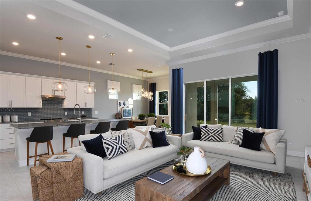 An open-concept living room and kitchen featuring white cabinetry, pendant lighting, and neutral furniture — 5778 SW 82ND TERRACE ROAD, OCALA, FL
