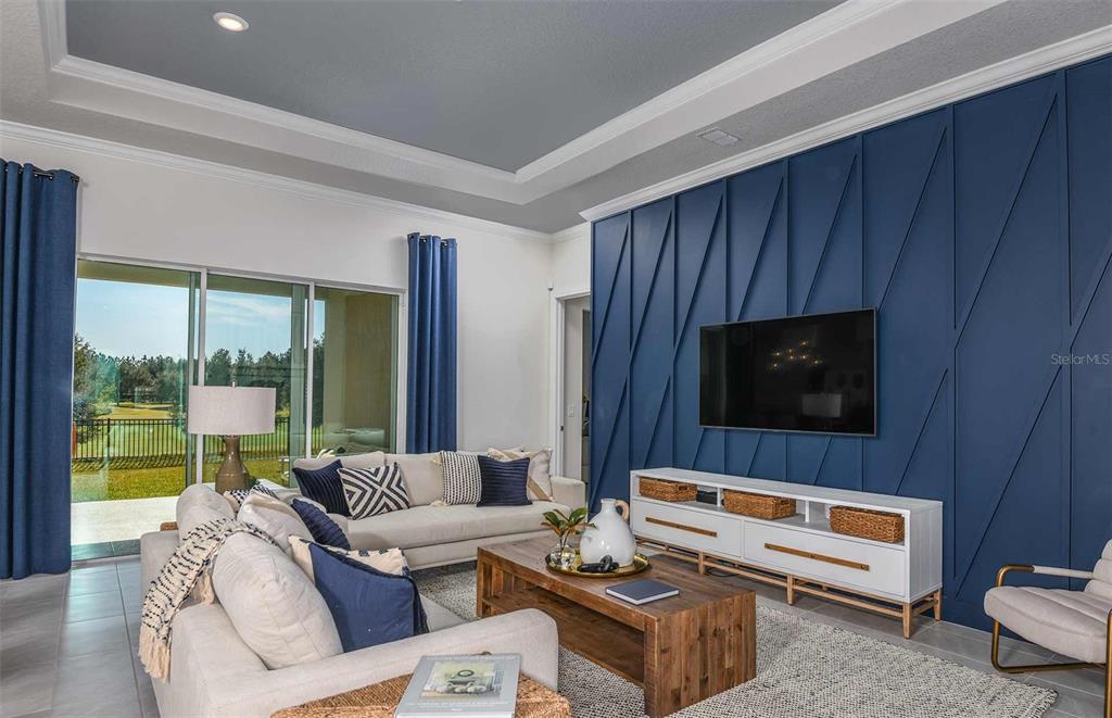 A living room features a blue geometric accent wall, a television, and a sectional sofa — 5778 SW 82ND TERRACE ROAD, OCALA, FL