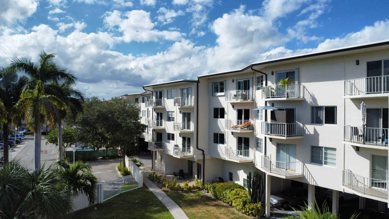 An exterior view of a multi-story apartment building with balconies and a ground-level parking area — 1967 S Ocean Boulevard # 221d, Pompano Beach FL 33062, POMPANO BEACH, FL