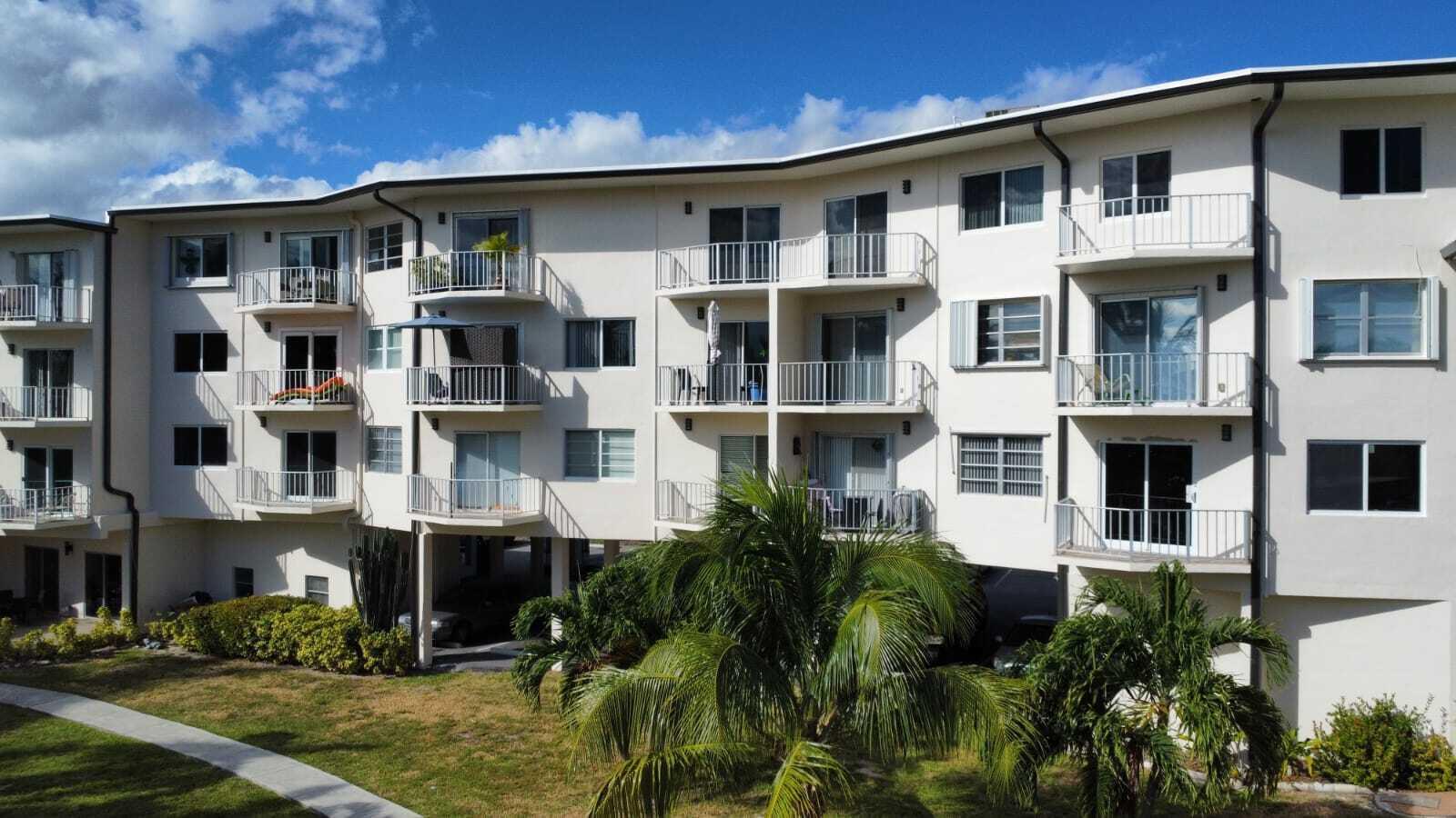 An exterior view of a multi-story apartment building with balconies and palm trees — 1967 S Ocean Boulevard # 221d, Pompano Beach FL 33062, POMPANO BEACH, FL