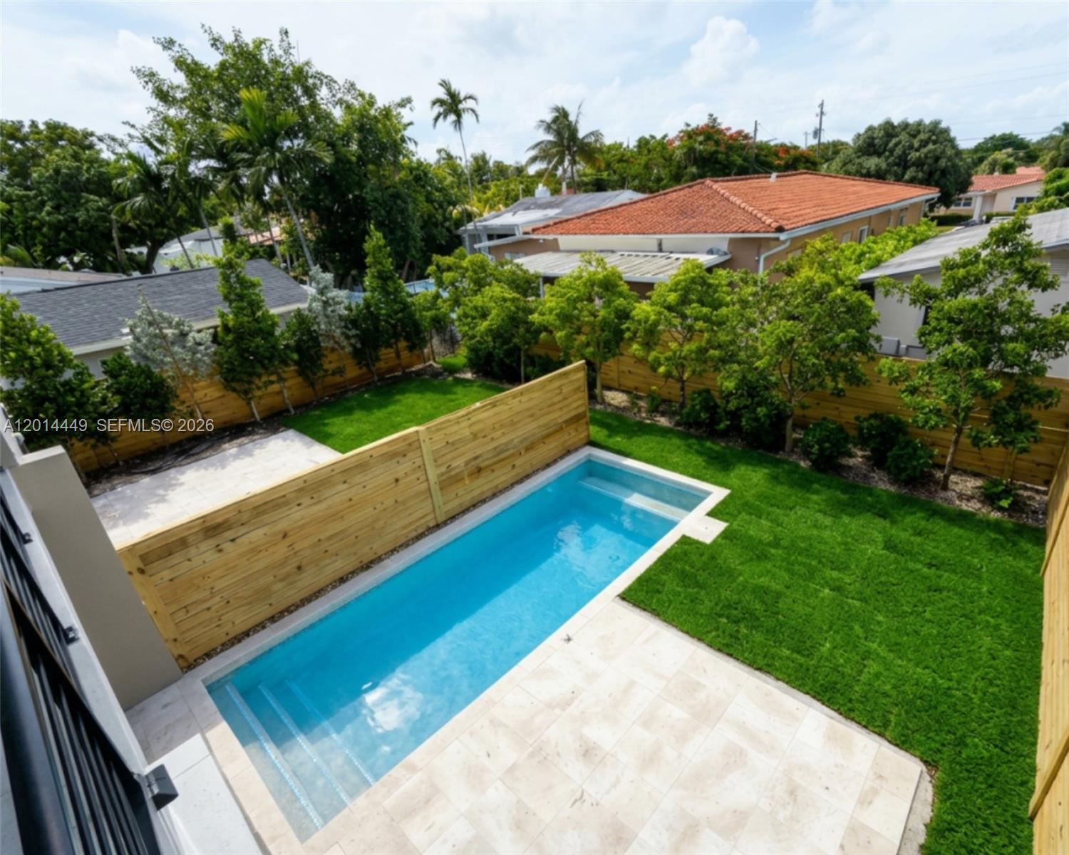 An elevated view of a backyard featuring a rectangular swimming pool, lawn, and wooden fencing — 1501 SW 21st St, Miami FL 33145, MIAMI, FL