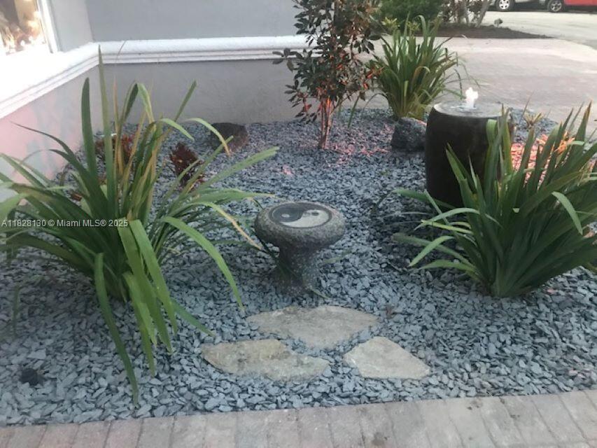 A small garden bed features gray gravel, a yin-yang stone, and a water fountain — 2108 NE 24th St, Wilton Manors FL 33305, WILTON MANORS, FL