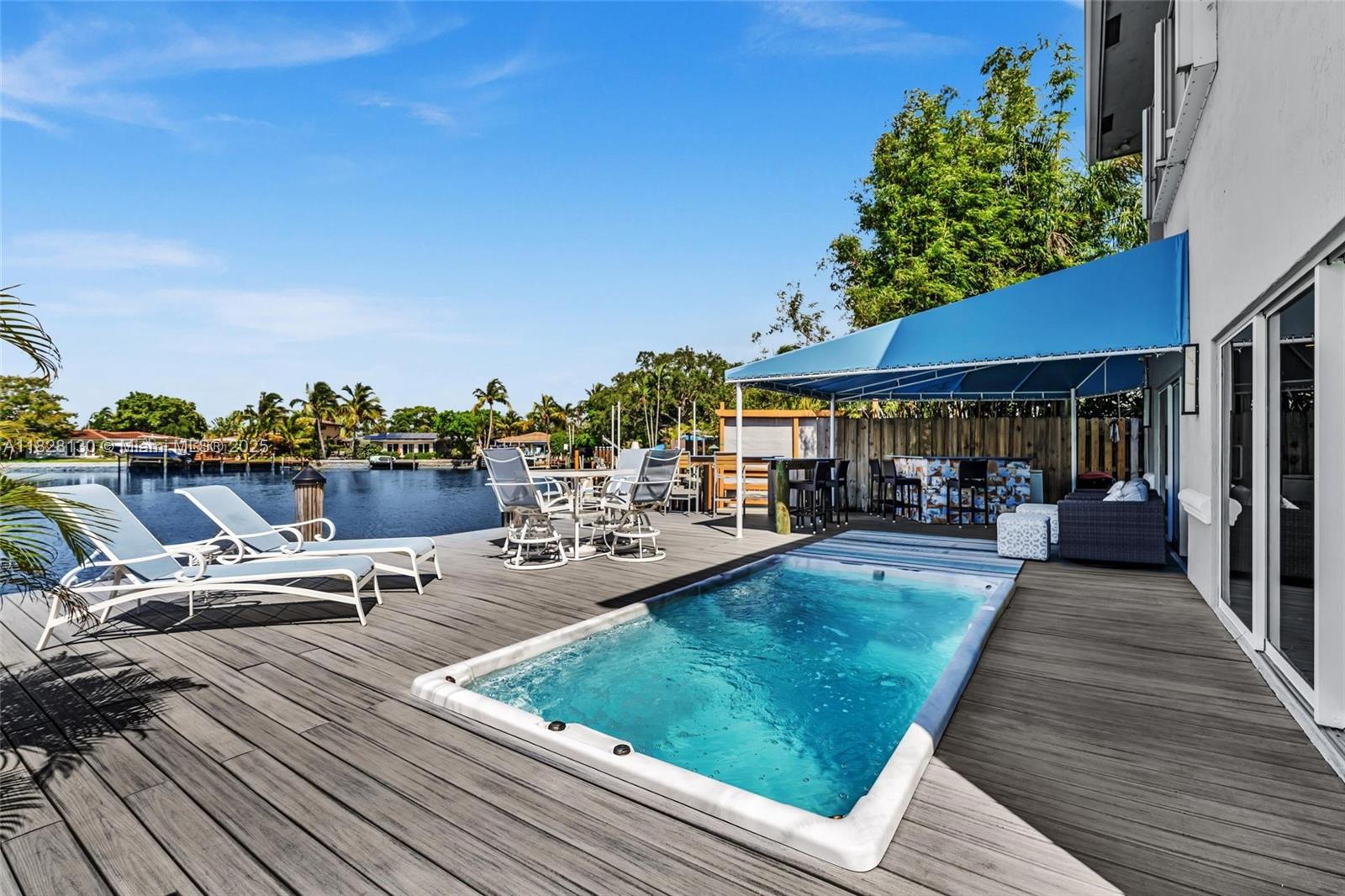 A wooden deck features a small rectangular pool, lounge chairs, and a covered outdoor bar area — 2108 NE 24th St, Wilton Manors FL 33305, WILTON MANORS, FL