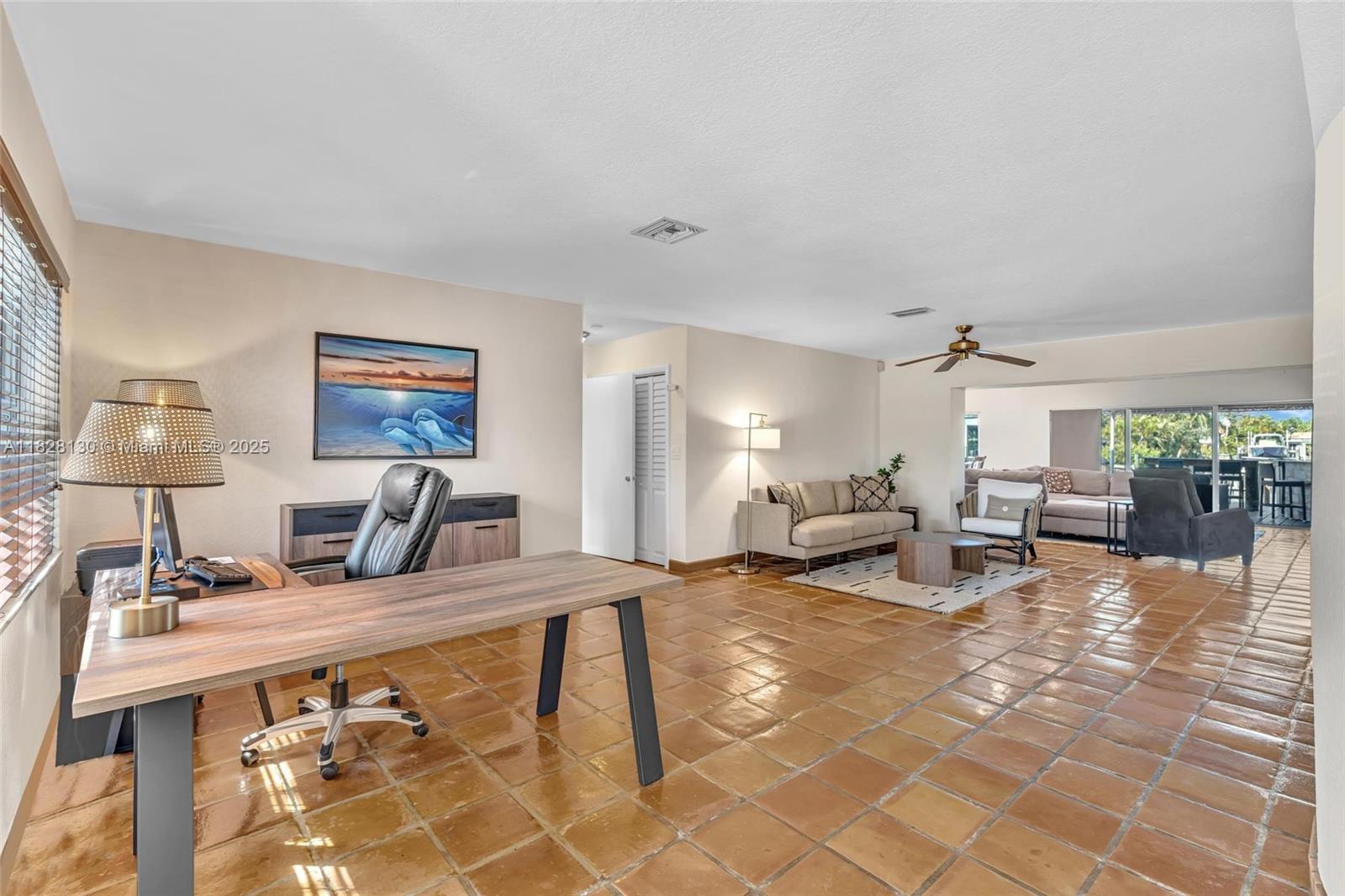 A spacious room features a desk, a seating area, and terracotta tile flooring throughout — 2108 NE 24th St, Wilton Manors FL 33305, WILTON MANORS, FL